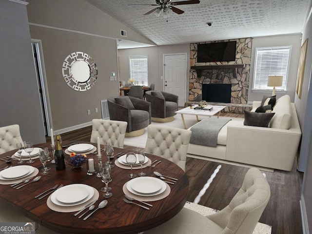 dining space with wood finished floors, a fireplace, ceiling fan, vaulted ceiling, and a textured ceiling