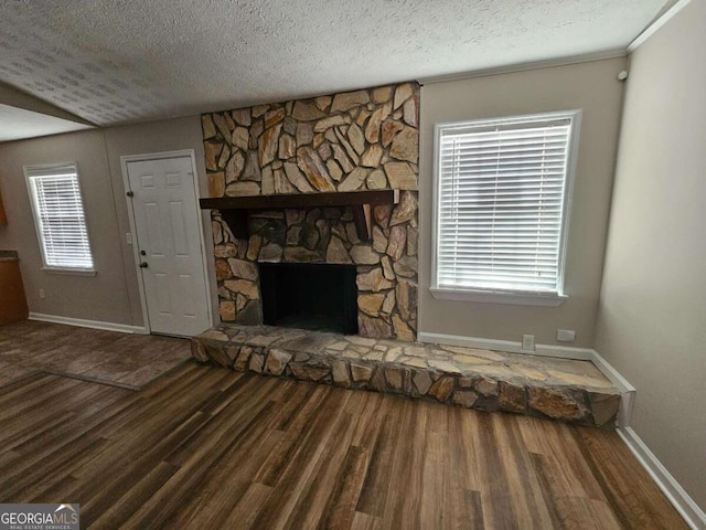 unfurnished living room featuring a textured ceiling, baseboards, and wood finished floors