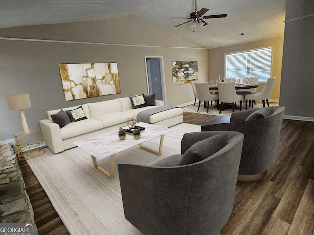 living room with wood finished floors, a ceiling fan, baseboards, vaulted ceiling, and a textured ceiling