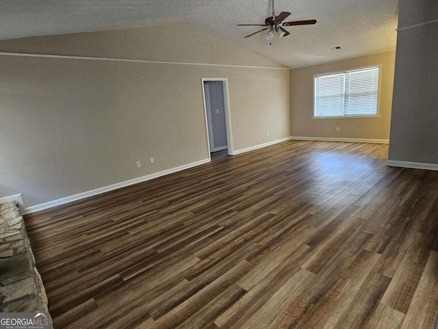 spare room with baseboards, lofted ceiling, dark wood-style floors, a textured ceiling, and a ceiling fan