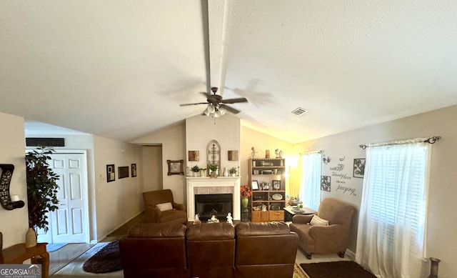 living area with a fireplace, vaulted ceiling, a ceiling fan, and visible vents