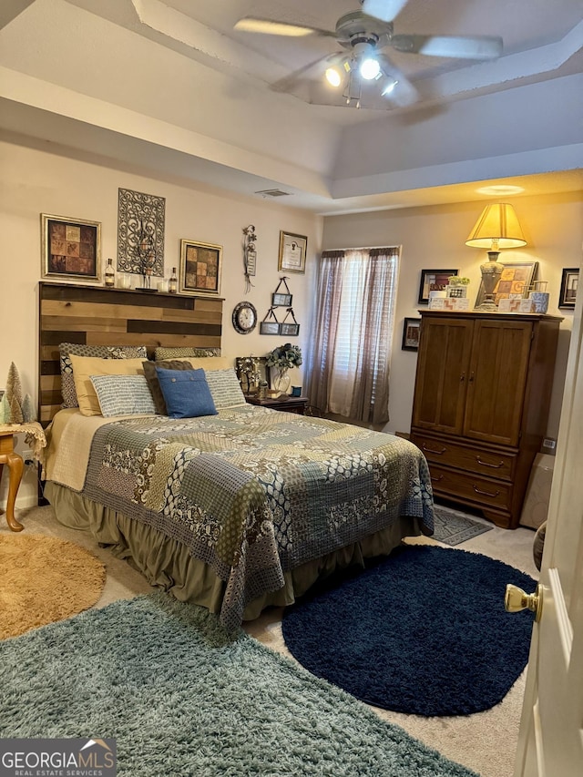 bedroom featuring visible vents, ceiling fan, a raised ceiling, and carpet