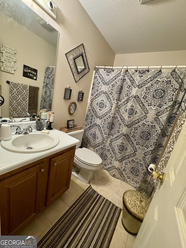 bathroom with tile patterned floors, toilet, a textured ceiling, and vanity