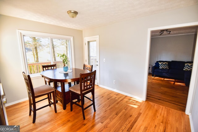 dining area featuring a textured ceiling, baseboards, and light wood-style floors