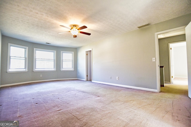 empty room with visible vents, a ceiling fan, a textured ceiling, carpet flooring, and baseboards