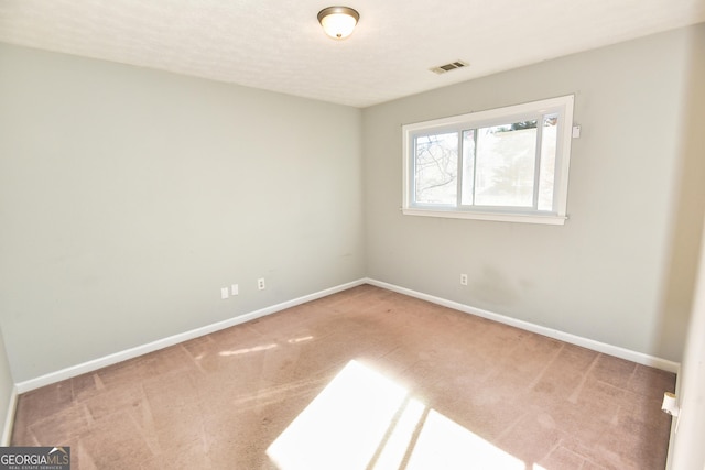 spare room with carpet flooring, baseboards, and visible vents