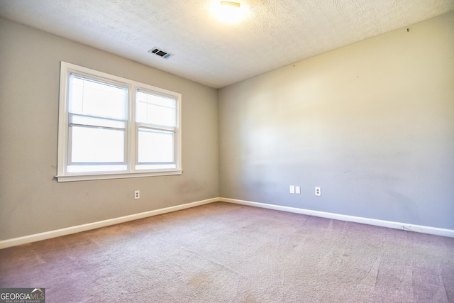 empty room with visible vents, a textured ceiling, and carpet