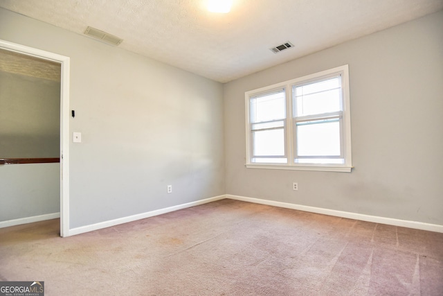 carpeted empty room with baseboards, visible vents, and a textured ceiling