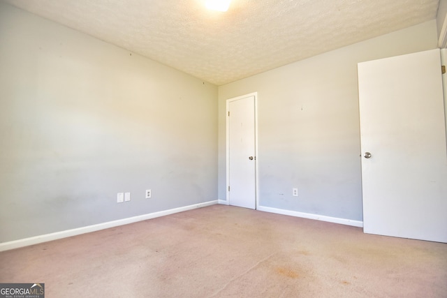 carpeted spare room featuring baseboards and a textured ceiling