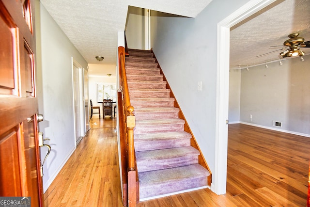 staircase featuring a textured ceiling and wood finished floors