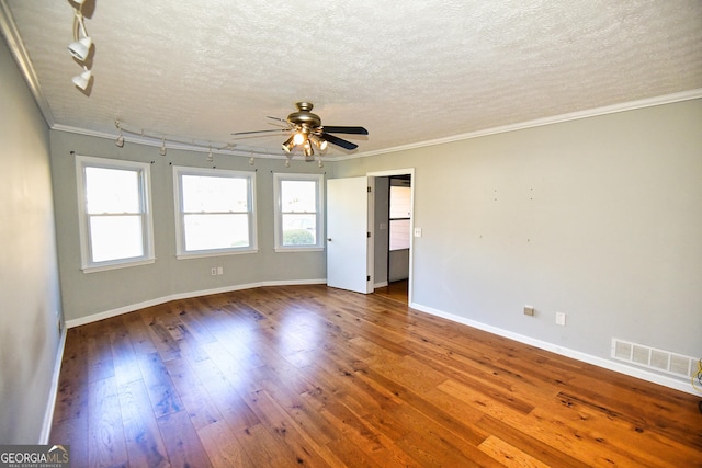 empty room featuring ornamental molding, visible vents, wood-type flooring, and ceiling fan