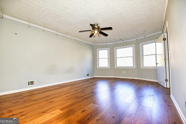 spare room featuring visible vents, dark wood-type flooring, ceiling fan, and a textured ceiling