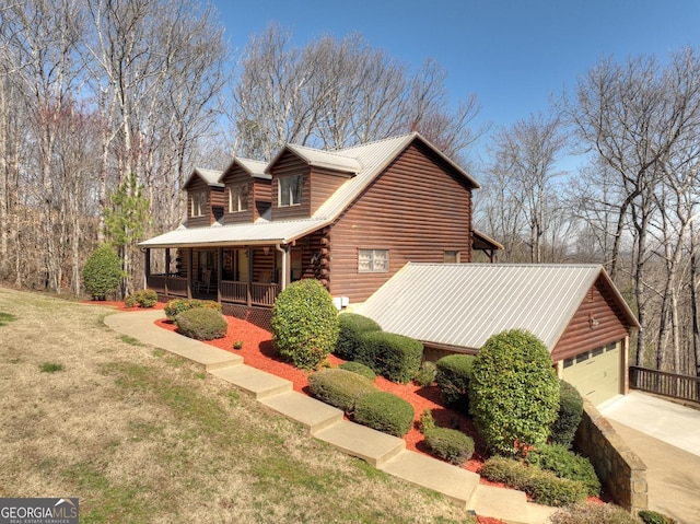 log home with a porch, a front yard, driveway, and metal roof