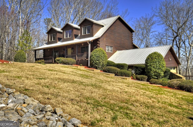 view of side of home featuring log siding, a porch, and a yard