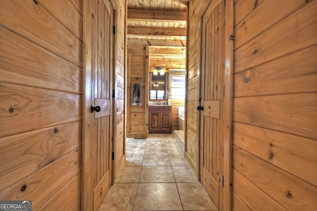 hall with light tile patterned floors, wood walls, and wooden ceiling