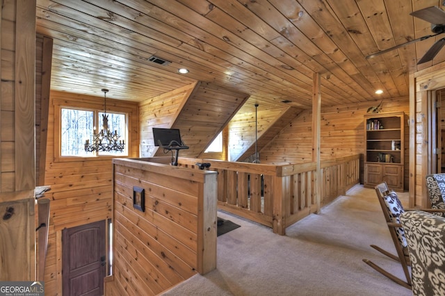 interior space with a notable chandelier, wooden walls, wood ceiling, and visible vents