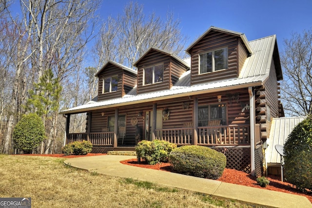 log cabin featuring a porch, log siding, a front lawn, and metal roof