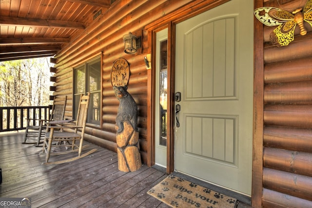 view of exterior entry with log veneer siding and a porch