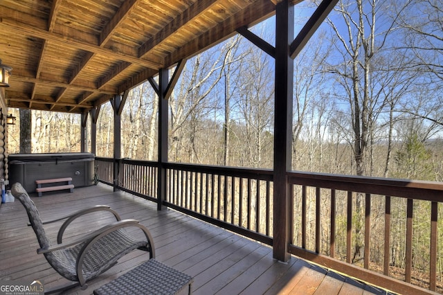 wooden deck featuring a view of trees and a hot tub