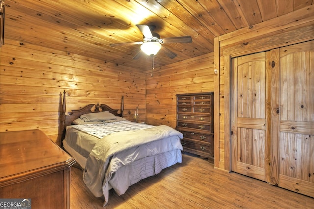 bedroom with a closet, wooden ceiling, wood walls, light wood finished floors, and ceiling fan