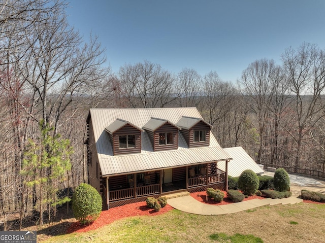 log home with metal roof, covered porch, log exterior, and a front yard