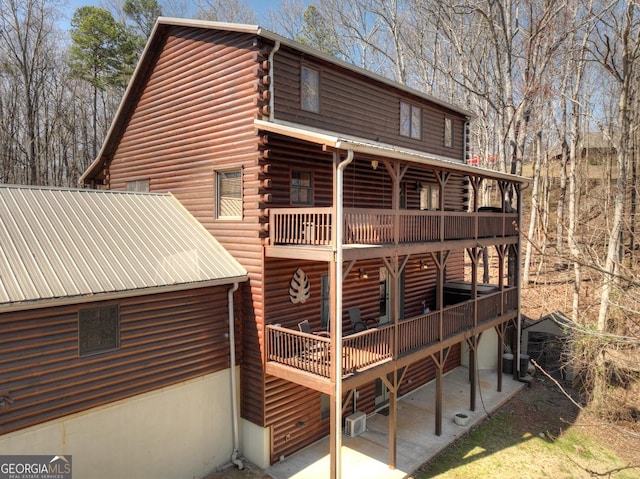 exterior space featuring a wall mounted AC, log exterior, and a wooden deck