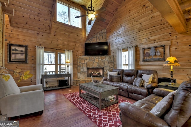 living room featuring wooden walls, wood ceiling, a fireplace, a ceiling fan, and wood-type flooring