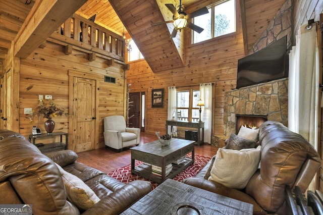 living area with wood finished floors, wooden walls, plenty of natural light, and a ceiling fan