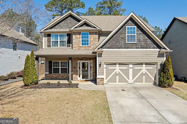 craftsman-style house featuring a front lawn, a garage, stone siding, and driveway