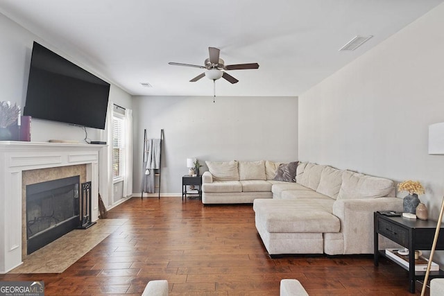 living room with visible vents, dark wood-style floors, a ceiling fan, and a tile fireplace