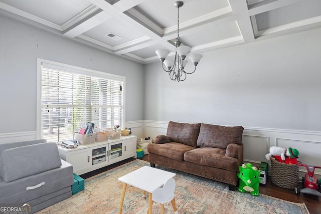 living area with visible vents, a chandelier, a wainscoted wall, beam ceiling, and wood finished floors