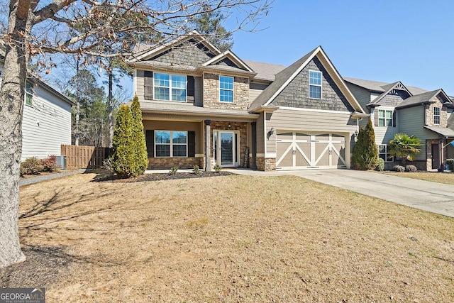 craftsman-style house with a front yard, fence, driveway, a garage, and stone siding