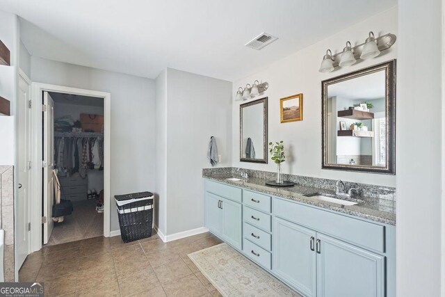 full bathroom featuring a sink, visible vents, a walk in closet, and double vanity