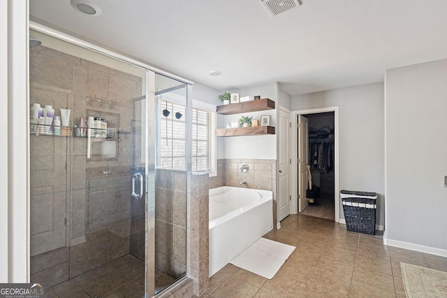 bathroom with visible vents, a walk in closet, a garden tub, a stall shower, and tile patterned floors