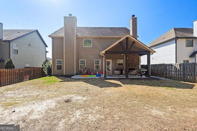 back of property with a patio area, a yard, a chimney, and a fenced backyard