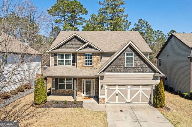 craftsman inspired home with stone siding, driveway, and a front lawn