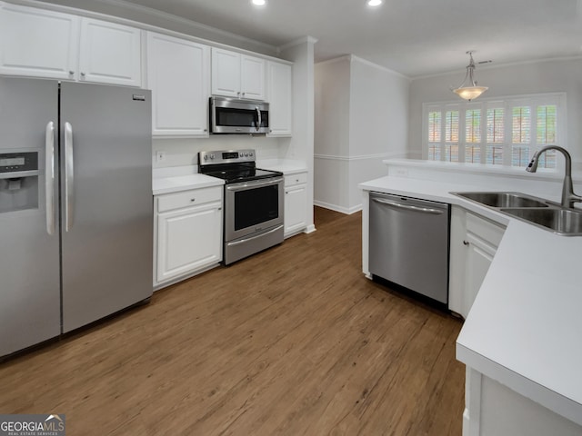 kitchen featuring ornamental molding, a sink, white cabinets, light wood-style floors, and appliances with stainless steel finishes