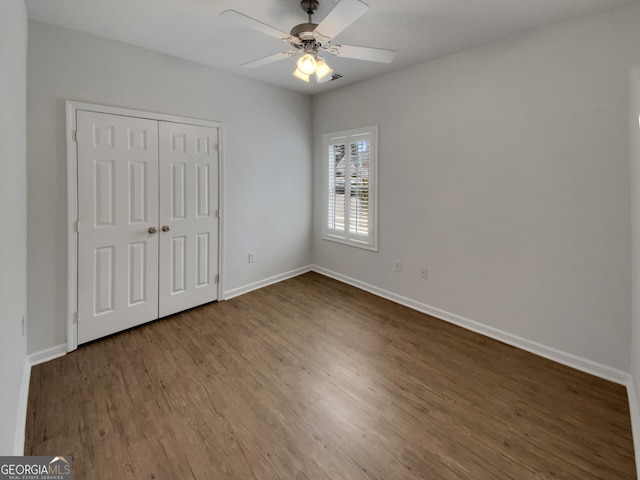 unfurnished bedroom featuring a closet, baseboards, wood finished floors, and a ceiling fan