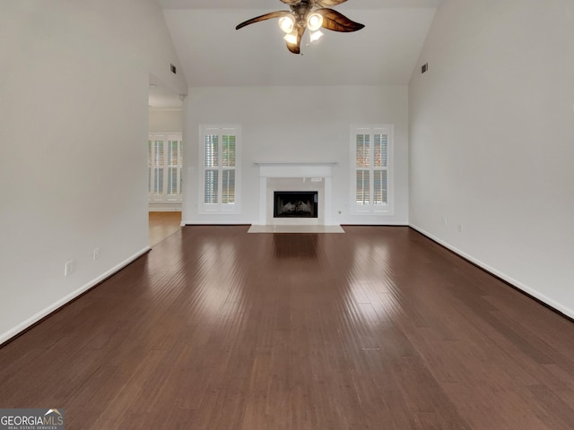 unfurnished living room featuring a high end fireplace, baseboards, wood finished floors, high vaulted ceiling, and a ceiling fan