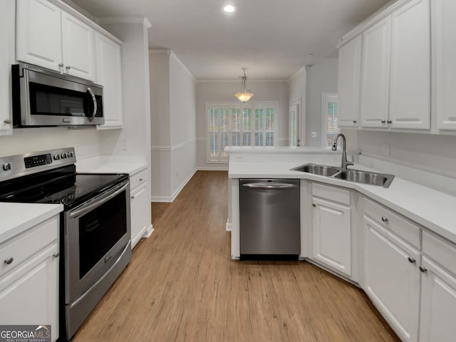 kitchen featuring white cabinets, stainless steel appliances, crown molding, and a sink