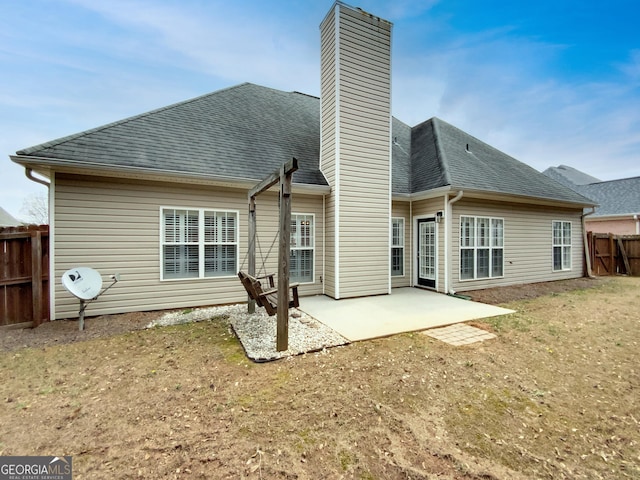 back of house featuring fence, roof with shingles, a chimney, and a patio area