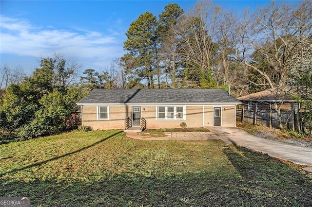 ranch-style house featuring driveway, a front yard, and fence