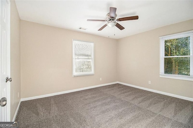 empty room with baseboards, visible vents, carpet floors, and ceiling fan