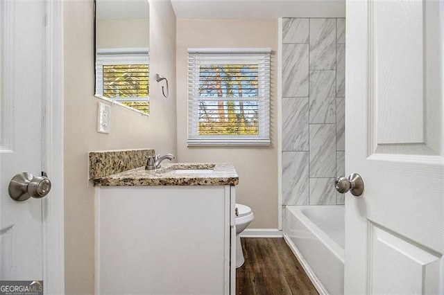 bathroom with vanity, toilet, wood finished floors, and baseboards