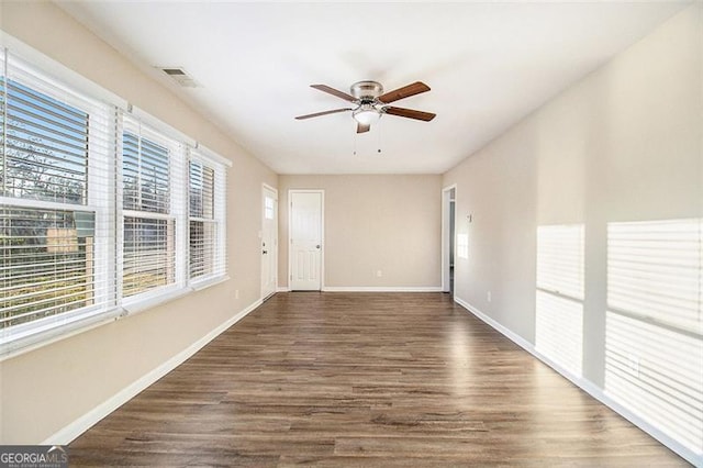 unfurnished room with visible vents, baseboards, a ceiling fan, and dark wood-style flooring