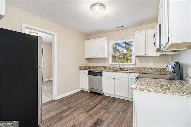 kitchen with a sink, appliances with stainless steel finishes, white cabinets, and dark wood finished floors