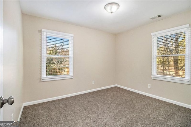 unfurnished room featuring baseboards and dark carpet