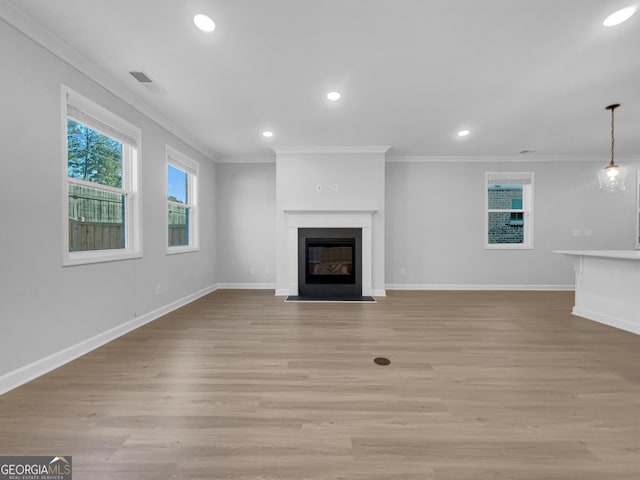 unfurnished living room with baseboards, a fireplace with flush hearth, light wood-style floors, and crown molding