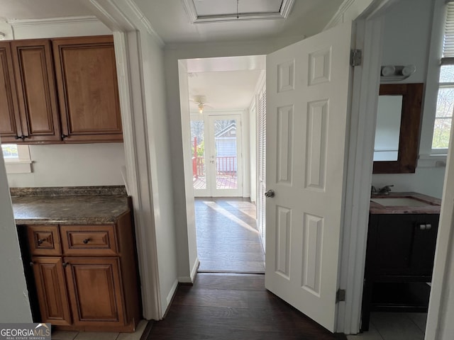 corridor featuring a sink, baseboards, dark wood-style flooring, and crown molding