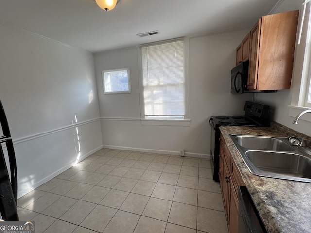 kitchen with dark countertops, visible vents, brown cabinets, black appliances, and a sink